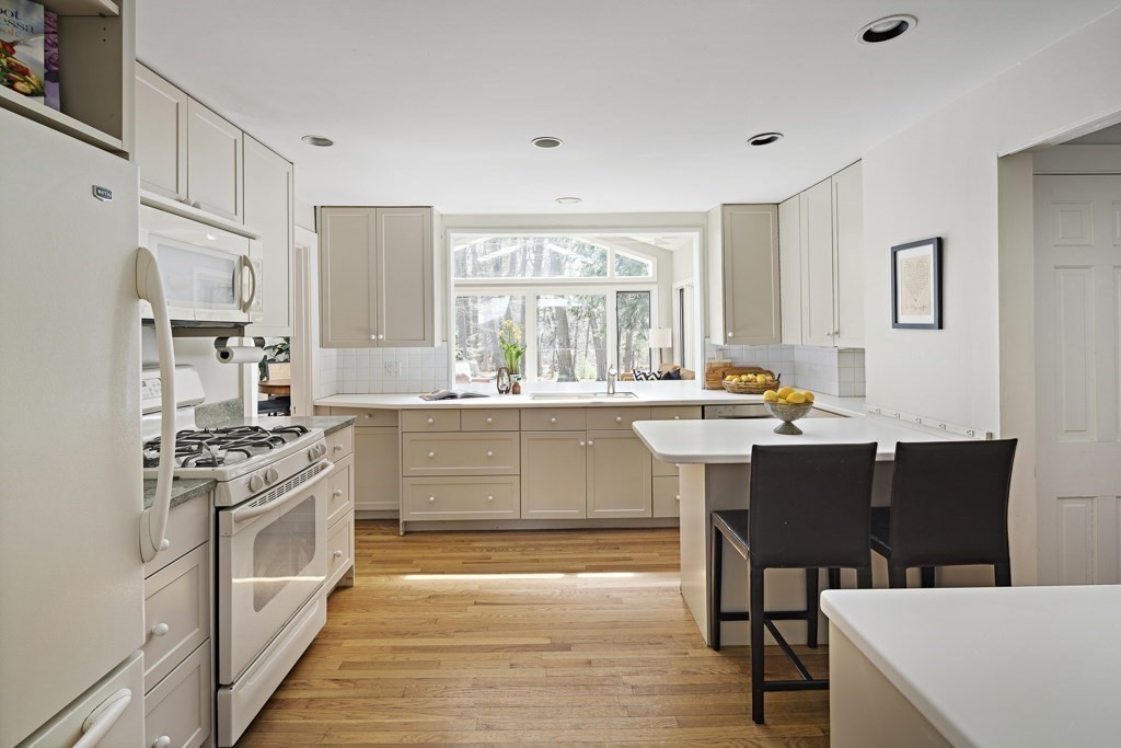 228 Islington Road Newton, MA 02466 - Photo 9 of 29 a kitchen with stainless steel appliances kitchen island granite countertop a stove a sink dishwasher and white cabinets with wooden floor