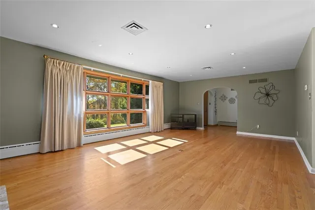 a view of an empty room with a window and wooden floor