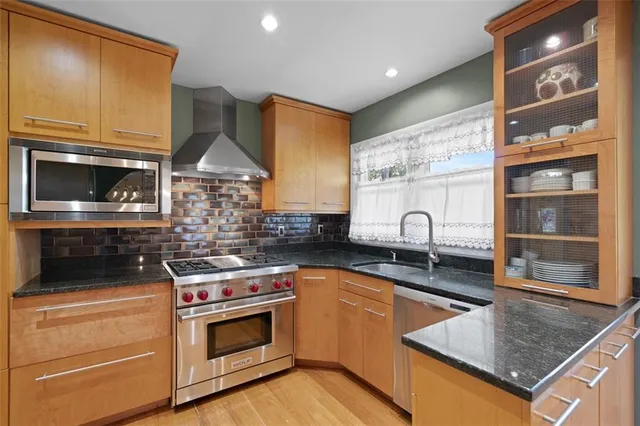 a kitchen with stainless steel appliances granite countertop a stove a sink and a microwave