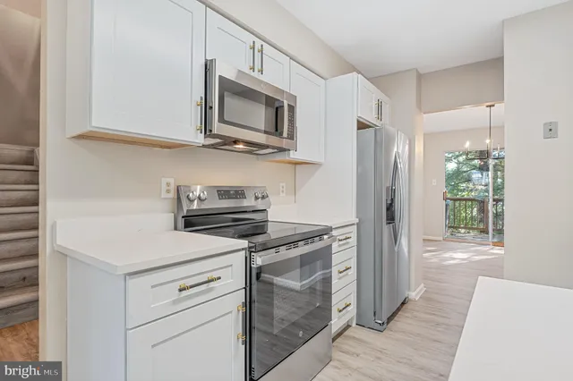 a kitchen with white cabinets and stainless steel appliances