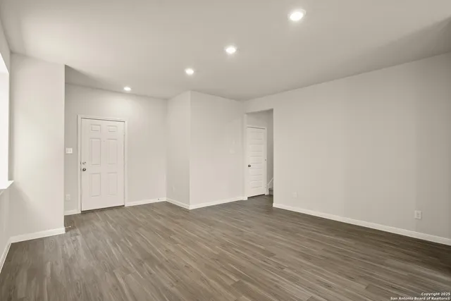 a view of an empty room with wooden floor and closet