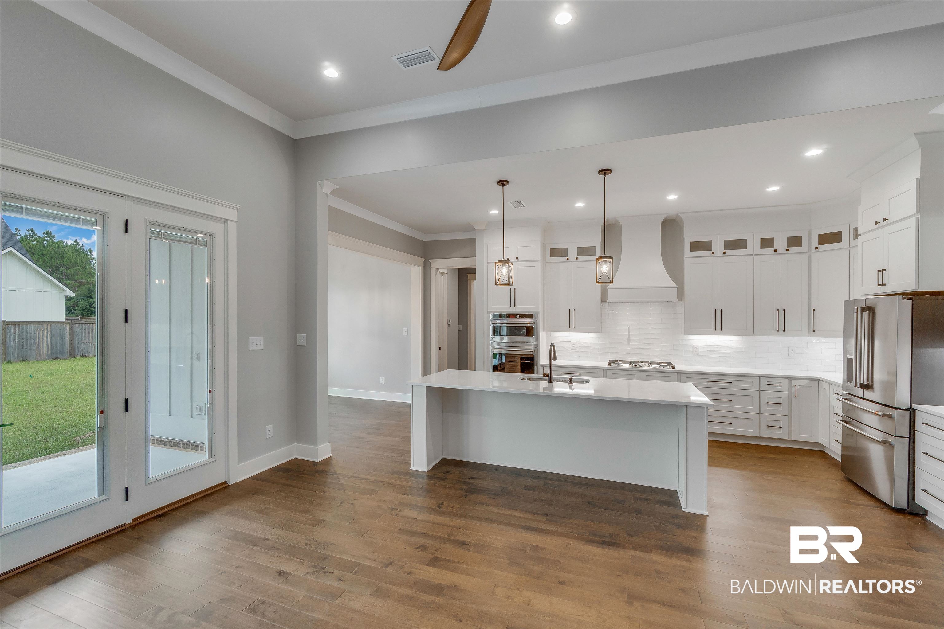 10985 Atrium Avenue Fairhope, AL 36532 - Photo 7 of 58 Kitchen featuring tasteful backsplash, a center island with sink, white cabinetry, ornamental molding, and glass insert cabinets