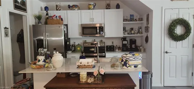 a kitchen with stainless steel appliances kitchen island granite countertop a refrigerator and microwave