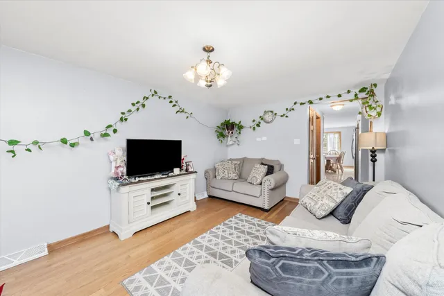 a living room with furniture a flat screen tv and a chandelier