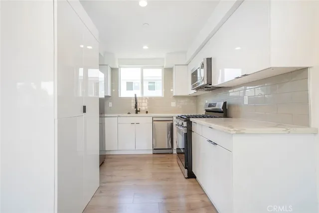 a kitchen with cabinets stainless steel appliances a sink and a stove