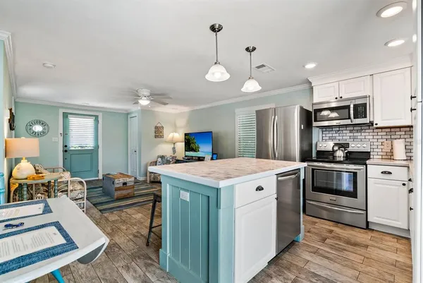 a kitchen that has a lot of white cabinets and stainless steel appliances
