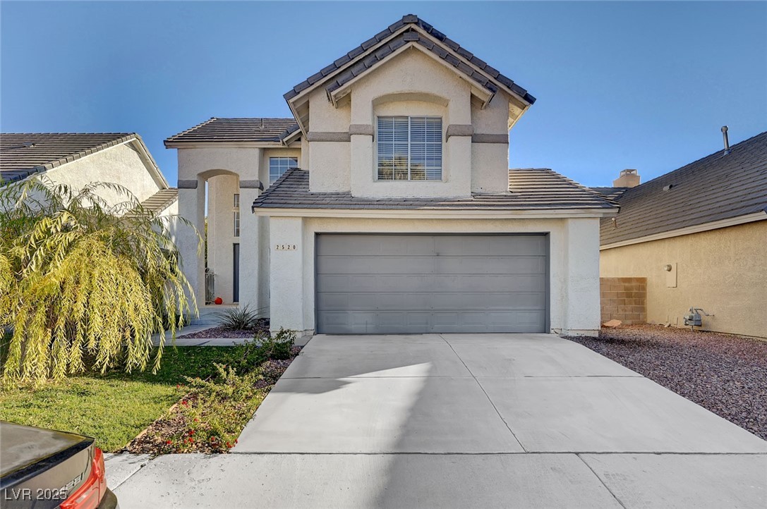 View of front facade with concrete driveway, a tiled roof, stucco siding, and a garage