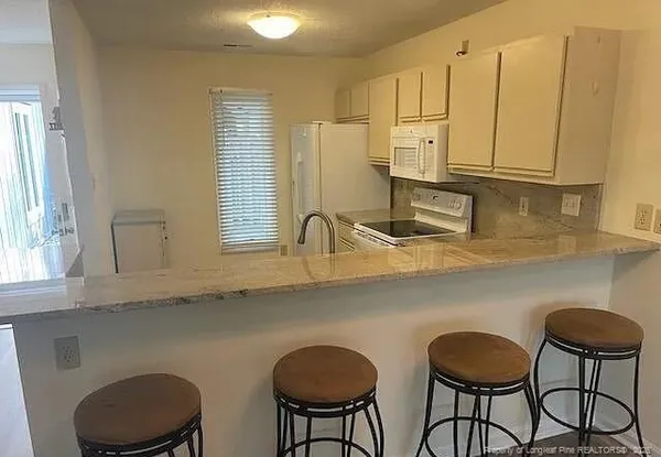 a kitchen with stainless steel appliances granite countertop a table chairs in it and wooden floors