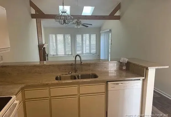 an empty room with a chandelier fan and windows