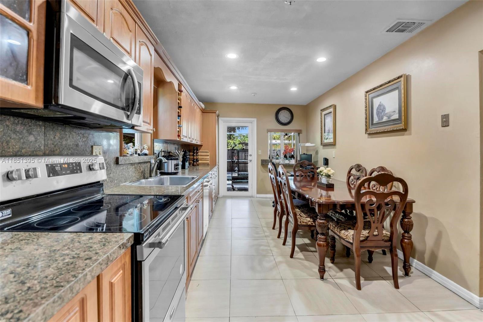 8711 Southwest 191st Street Cutler Bay, FL 33157 - Photo 20 of 56 a kitchen with stainless steel appliances granite countertop a stove top oven a sink a dining table and chairs