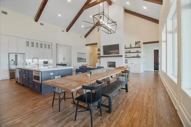 a dining room with stainless steel appliances kitchen island granite countertop a table chairs and a wooden floor