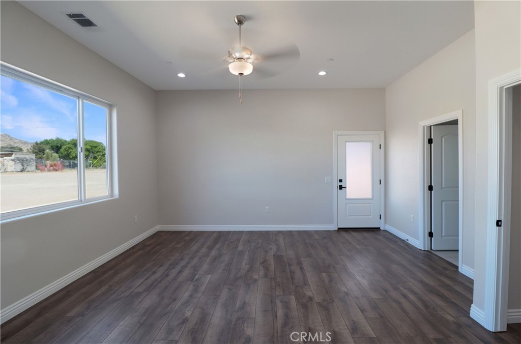14785 Tigertail Road Apple Valley, CA 92307 - Photo 7 of 20 a view of an empty room with wooden floor and a window