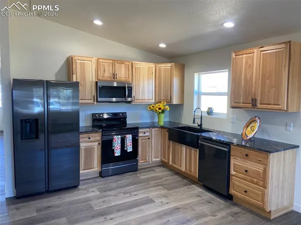 a kitchen with granite countertop a refrigerator stove top oven and sink