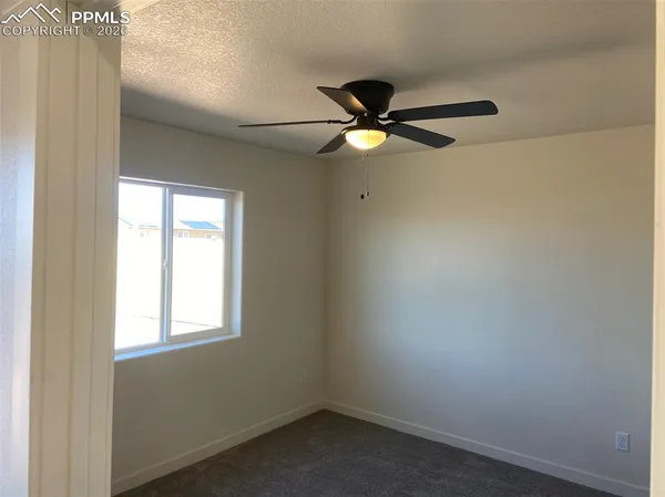 an empty room with a window and a fan