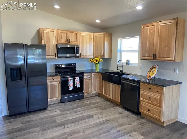 a kitchen with stainless steel appliances granite countertop a stove a sink and a refrigerator