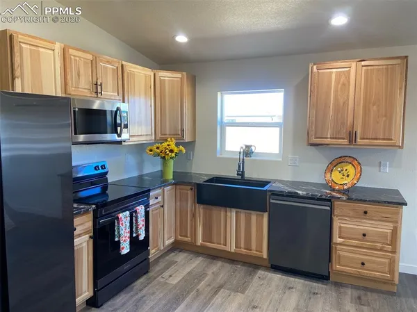 a kitchen with stainless steel appliances granite countertop a stove a sink dishwasher and microwave with wooden floor