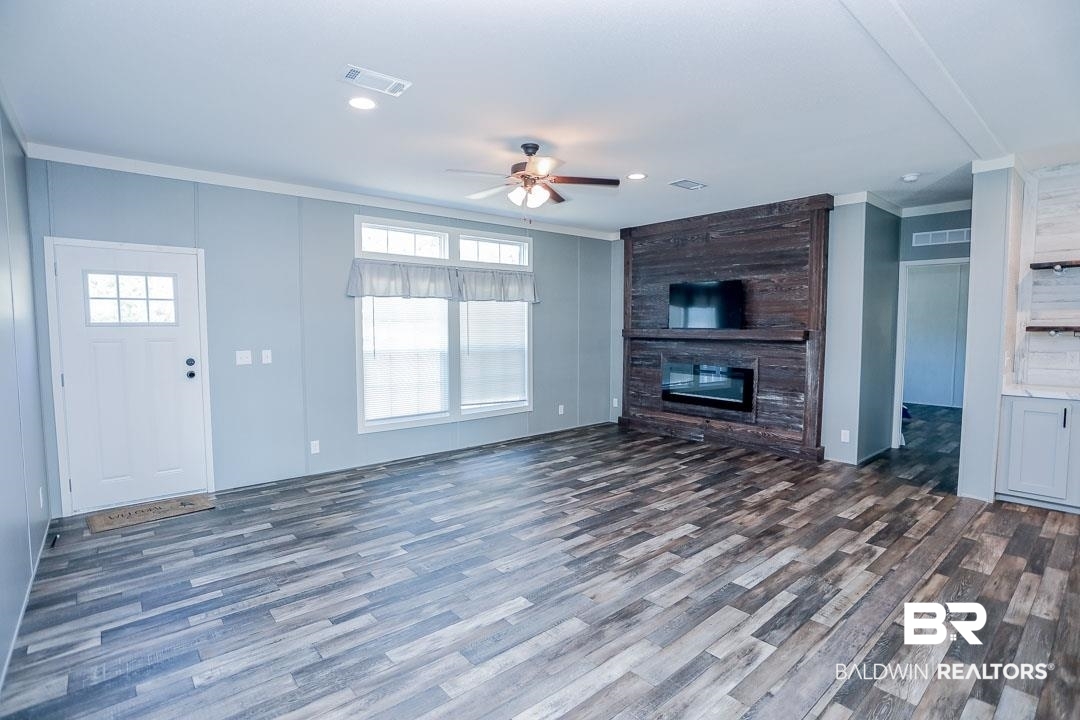 19180 Horseshoe Circle Seminole, AL 36574 - Photo 4 of 38 Unfurnished living room featuring crown molding, dark wood finished floors, a large fireplace, ceiling fan, and recessed lighting