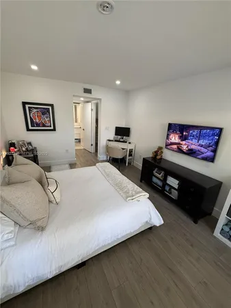 a spacious bedroom with a bed a couch and a flat screen tv
