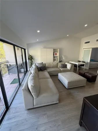 a living room with couches and large mirror with wooden floor