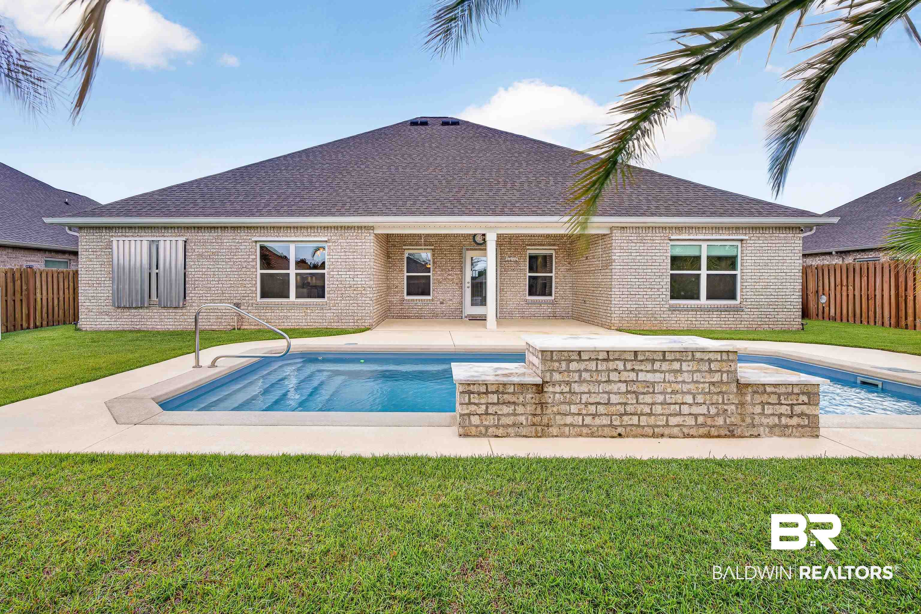 1724 Partridge Street Foley, AL 36535 - Photo 51 of 62 Expansive backyard featuring a rectangular swimming pool with integrated steps, a raised brick-clad hot tub, and a surrounding concrete patio