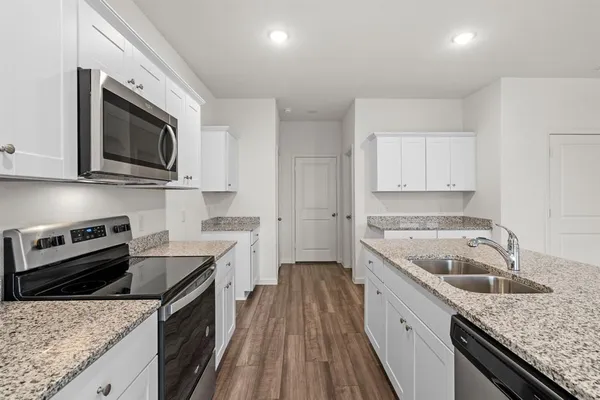 a kitchen with granite countertop a sink stove and cabinets