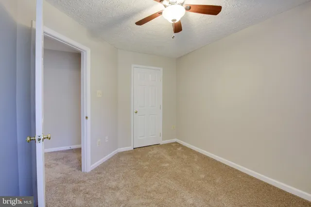 an empty room with a ceiling fan and carpet