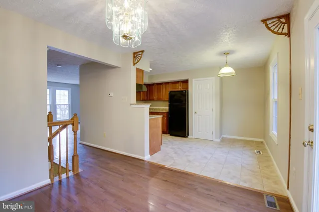 a view of a hallway with wooden floor and a kitchen