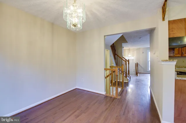 a view of a hallway with wooden floor and a chandelier