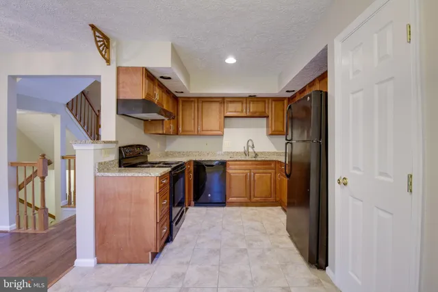 a kitchen with stainless steel appliances granite countertop a refrigerator a sink a stove and a refrigerator