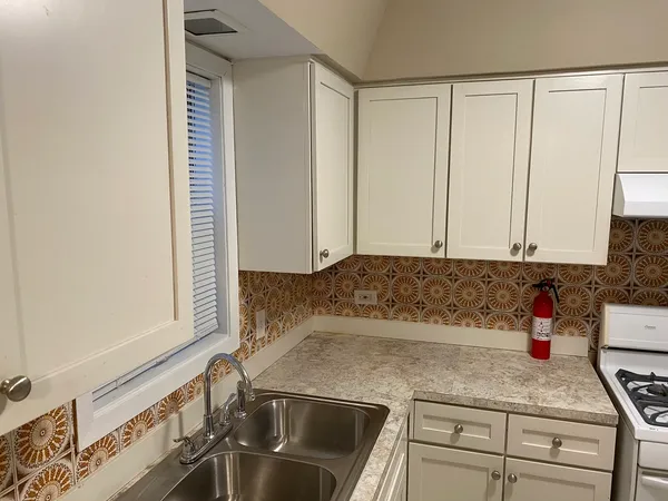 a kitchen with granite countertop a sink a stove and cabinets