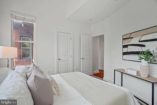 a bedroom with a bed and a potted plant on the dresser