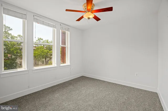 an empty room with a window and a fan