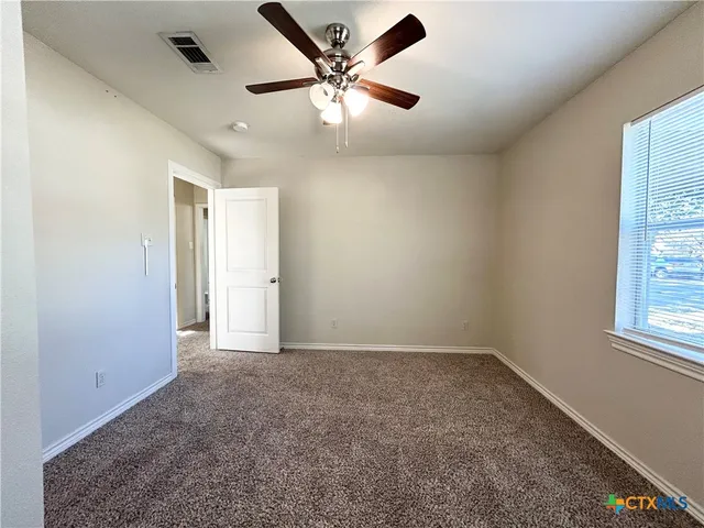 an empty room with windows and fan