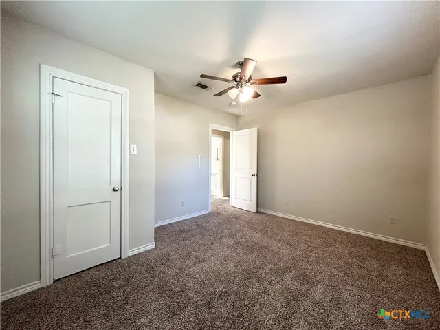 a view of an empty room with a chandelier fan