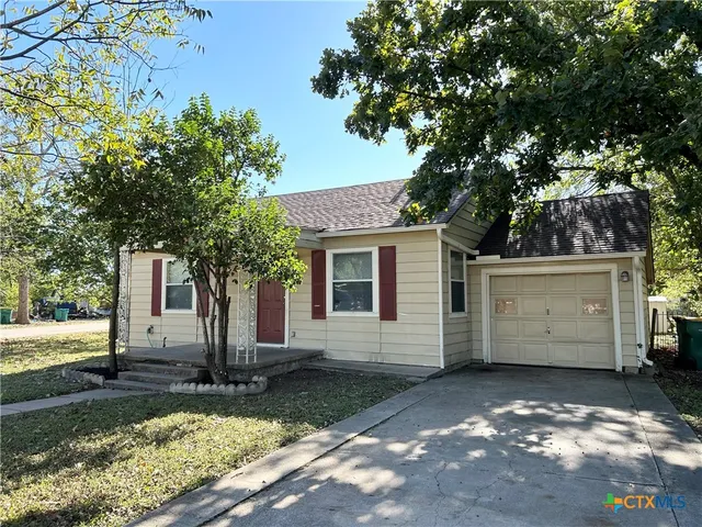 a view of a white house with a yard and large tree