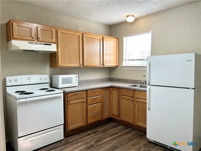 a kitchen with a refrigerator sink and cabinets