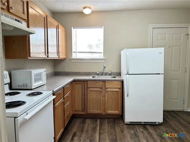 a kitchen with a refrigerator a stove a microwave and wooden floor