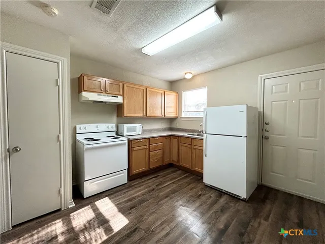 a kitchen with a refrigerator a sink and wooden floor
