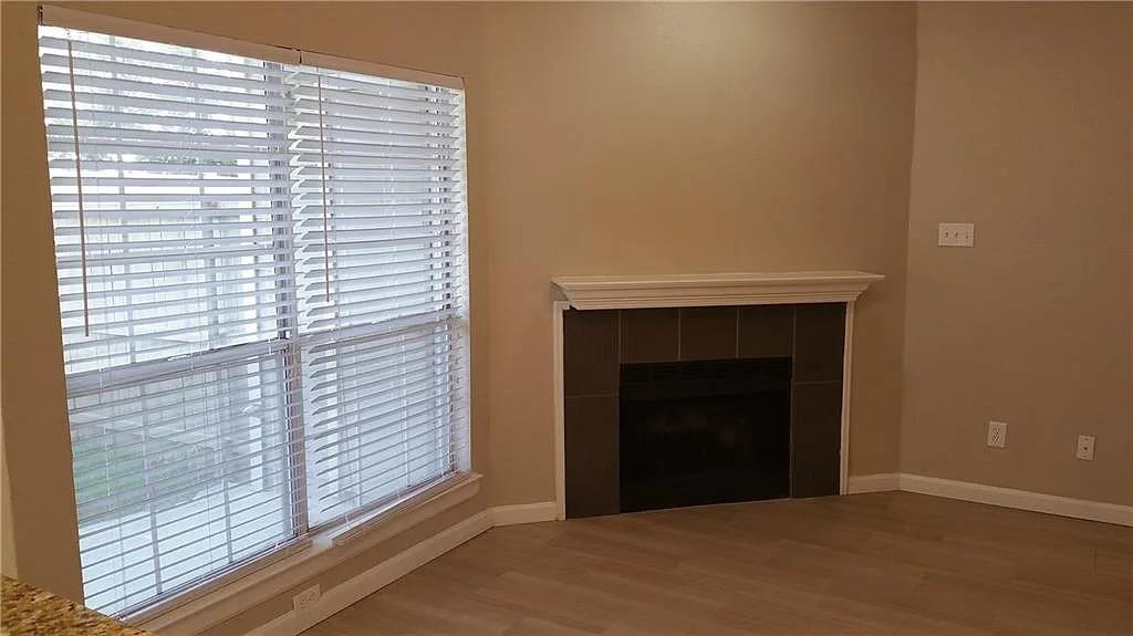 4113 Esters Road, Unit 604 Irving, TX 75038 - Photo 5 of 6 Neutral wall paint, wood-finish flooring, white window blinds, tiled fireplace surround, and a classic white mantel