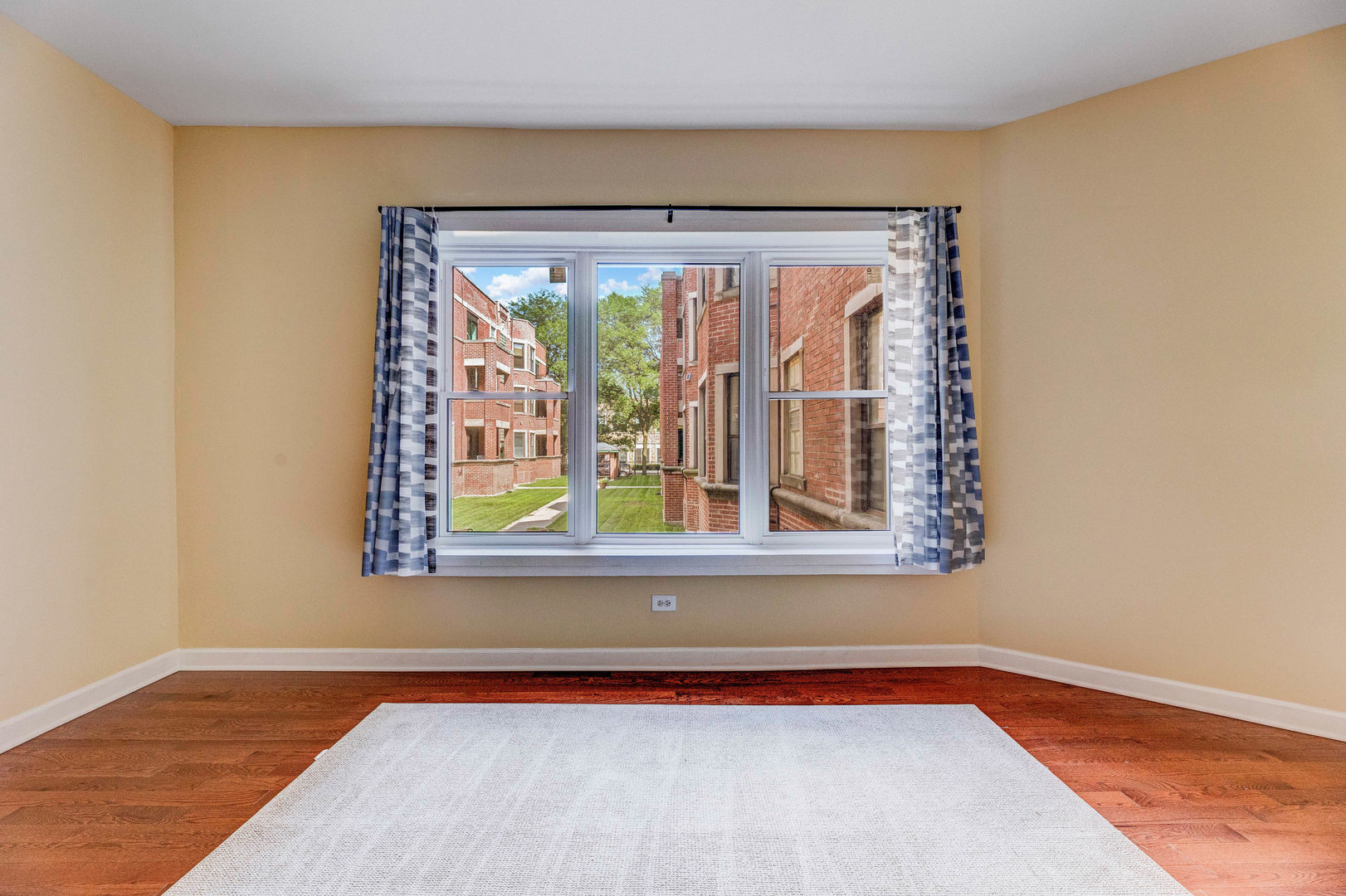 6104 South Dorchester Avenue, Unit 1S Chicago, IL 60637 - Photo 3 of 16 a view of an empty room with a window and wooden floor