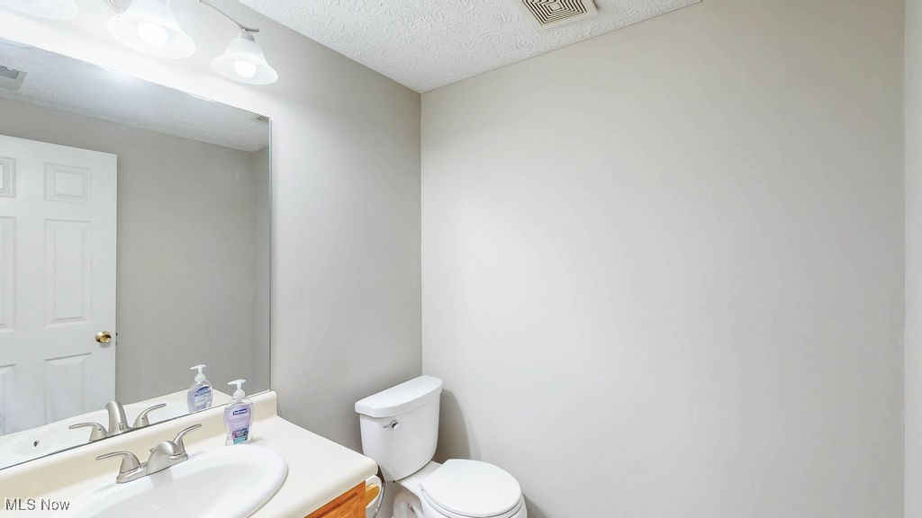 1426 Loop Road, Unit 1426 Kent, OH 44240 - Photo 5 of 40 Half bathroom featuring vanity and a textured ceiling. Located off the entry foyer.
