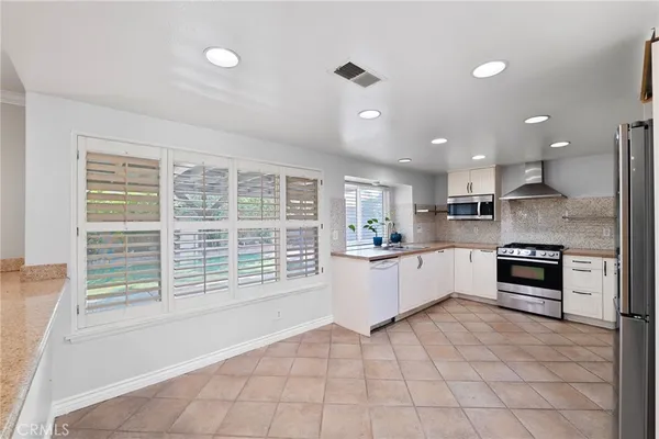 a large kitchen with kitchen island granite countertop a stove a sink a counter space and cabinets