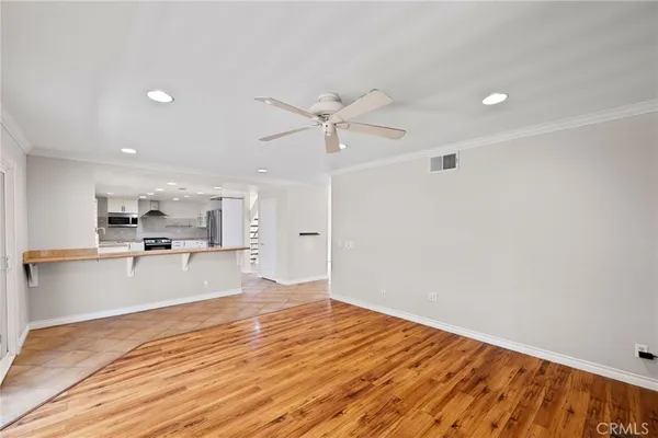 a view of kitchen and empty room with wooden floor
