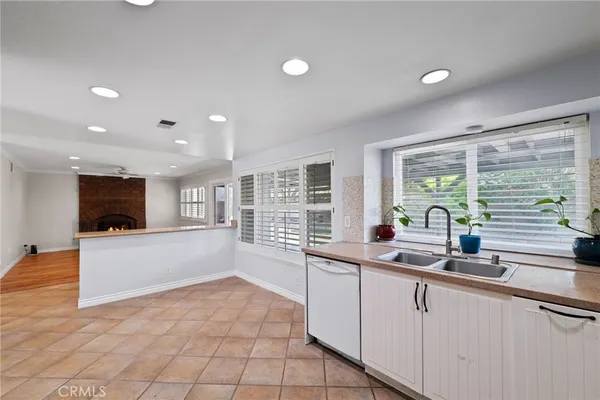 a large white kitchen with granite countertop a sink and a large window