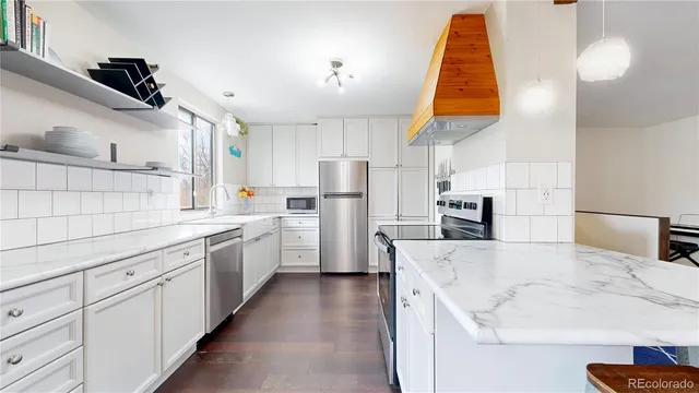 a kitchen with white cabinets and refrigerator