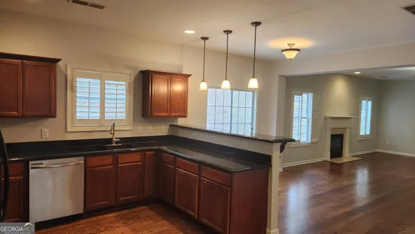 a kitchen with stainless steel appliances granite countertop a sink a counter space and a window