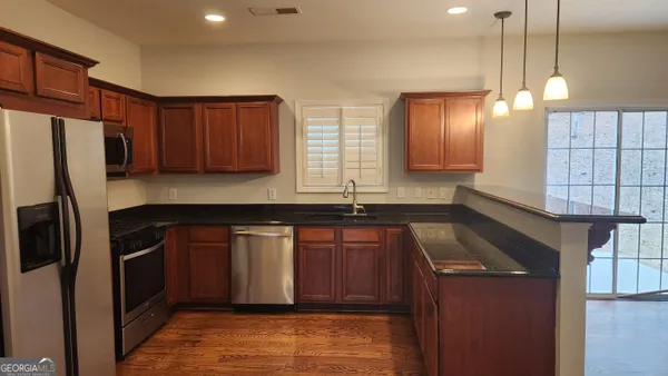 a kitchen with stainless steel appliances granite countertop a refrigerator a sink dishwasher a stove and a refrigerator