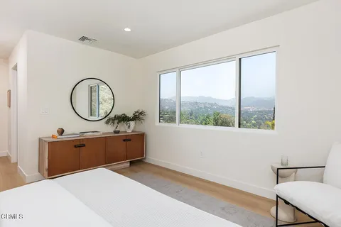 a bed room with a bed a mirror and a large window