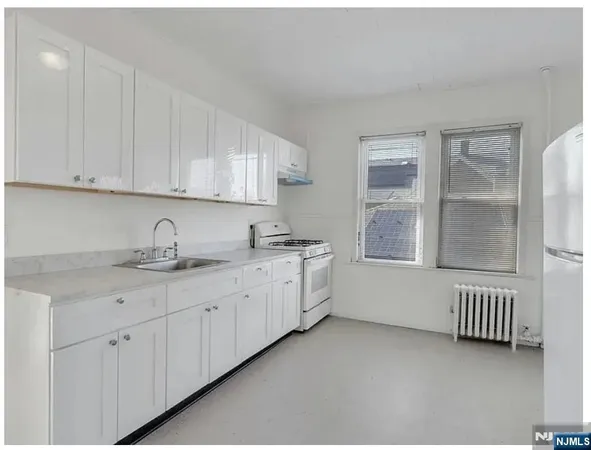 a utility room with granite countertop white cabinets sink and window