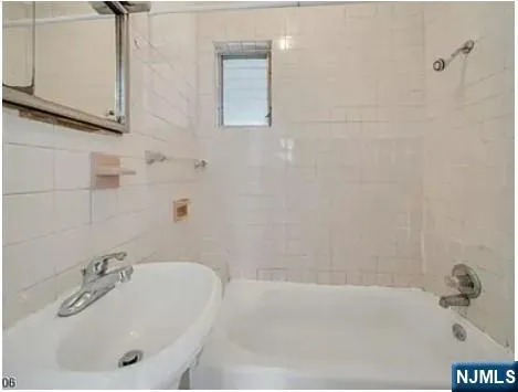 a bathroom with a tub sink and mirror